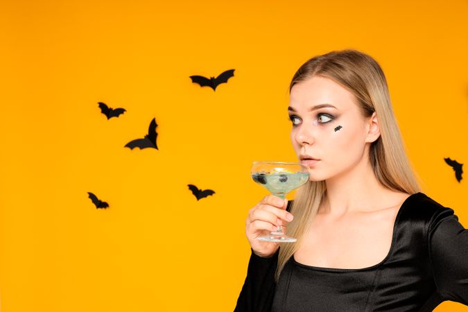 A woman at a party in the style of Halloween with a cocktail in her hands