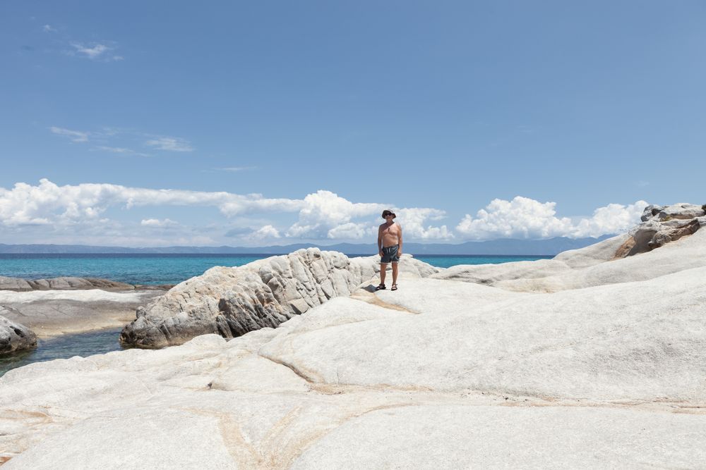 Man standing on amazing white stony seaside