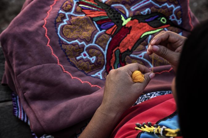 Person holding a yellow thread for embroidery