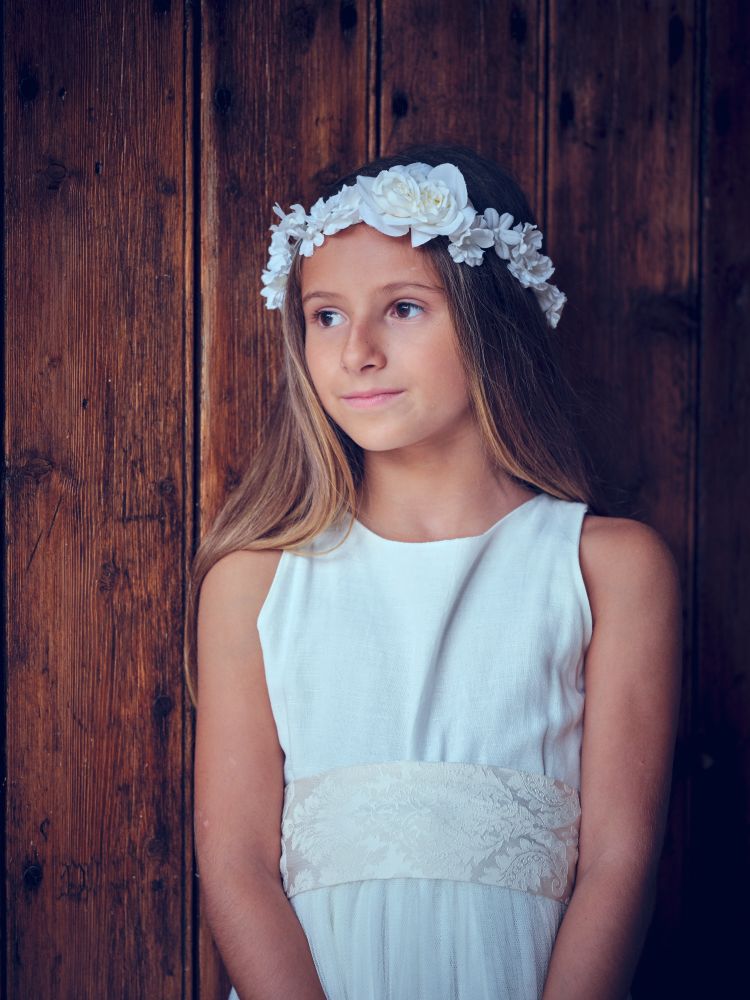 Cute girl in dress and wreath near wooden wall