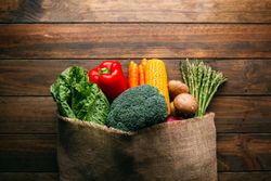 Linen sack with assorted vegetables on table