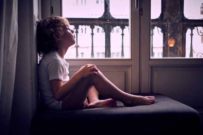Peaceful kid napping on pouf near window