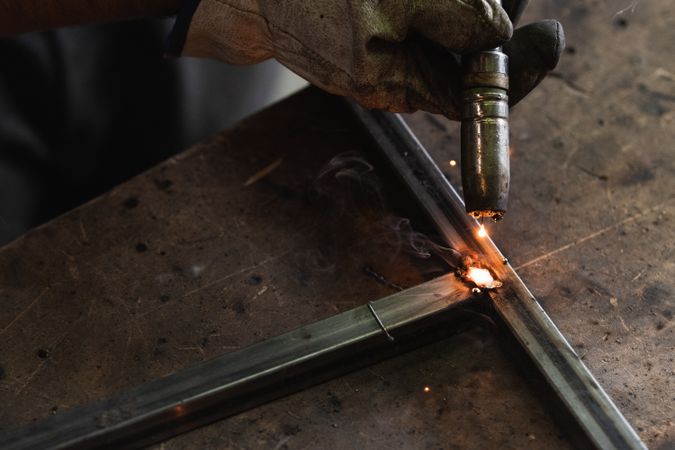 Crop master welding metal pieces at workbench