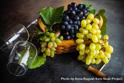 Box of fresh green & red grapes on grey kitchen counter with two wine glasses 5zrdJQ