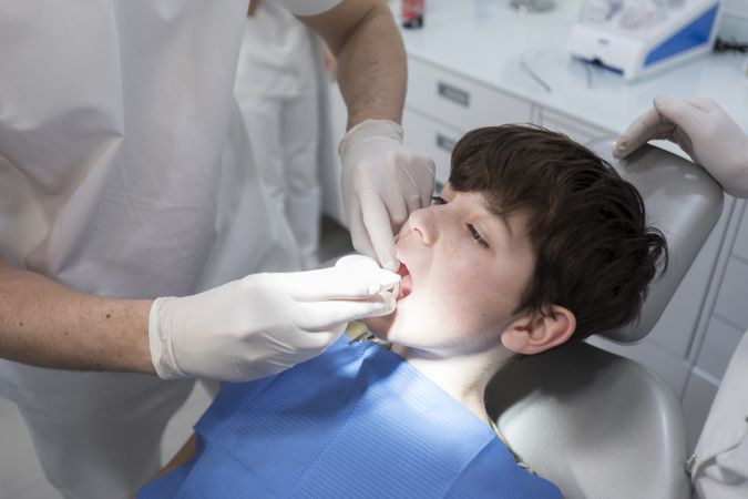 Dentist examining male teenager's teeth in clinic