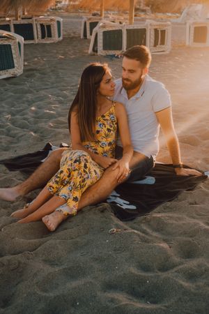 Tender couple embracing on beach towel in sunlight on sand