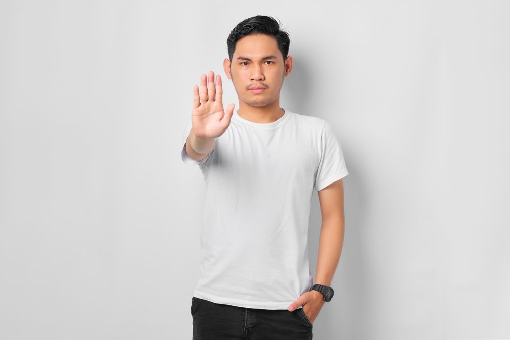 Asian male in grey studio gesturing to stop