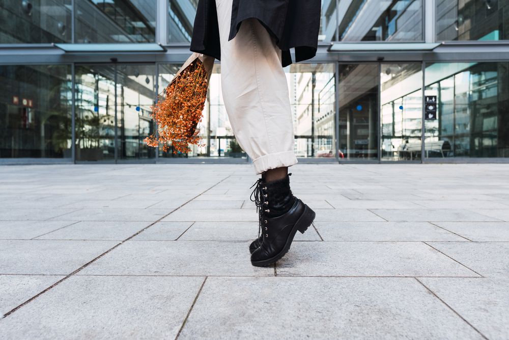 Crop woman with bouquet tiptoeing on street