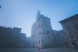 Aged stone buildings on square in mist