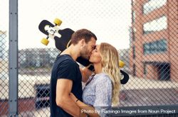 Man and woman kissing with man holding skateboard to shoulder 5Xmeo4