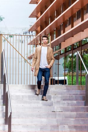 Man in jeans and autumn coat walking down stairs outside