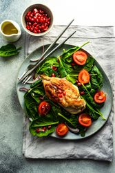 Fresh organic salad with chicken, spinach, tomato and pomegranate seeds
