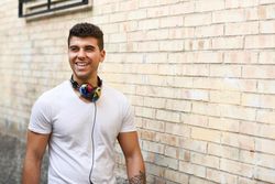 Happy young man with colorful headphones standing outside