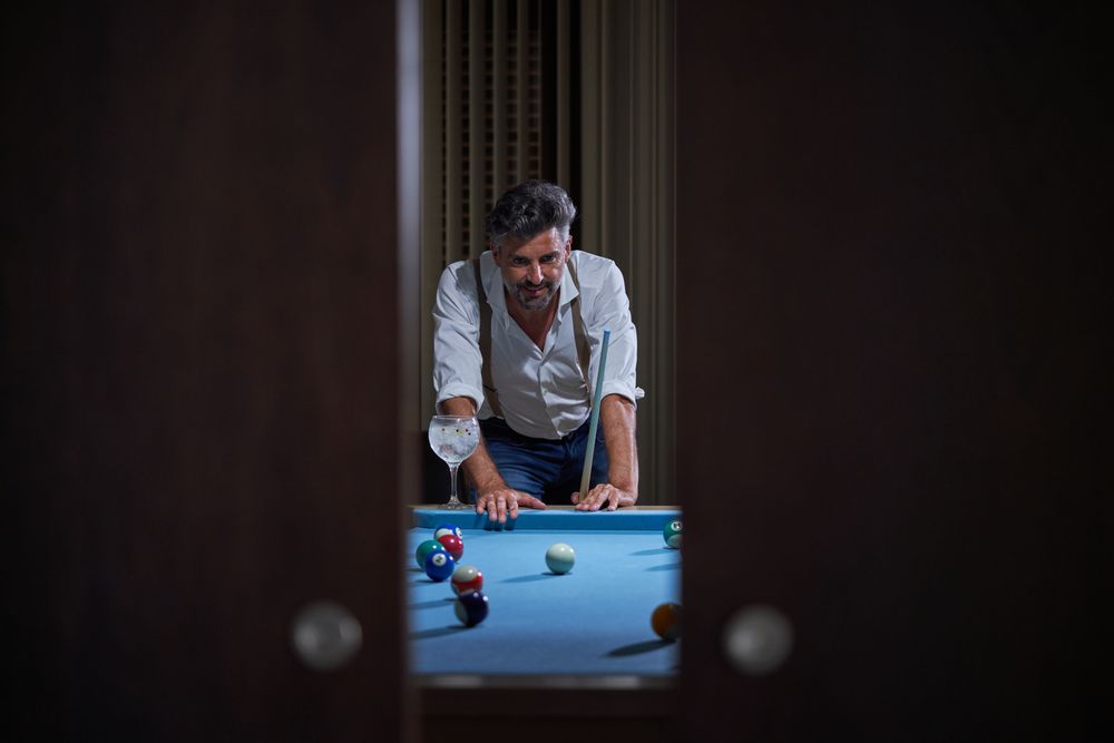 Male with cue playing billiards at home