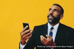 Serious Black businessman having a video call on a smartphone screen while looking up 42Zl34