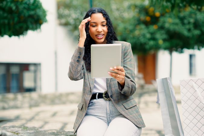 A young woman uses her tablet outdoors, blending technology with the beauty of nature