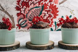 Three Chocolate cakes in the cup with currants and sugar glass.