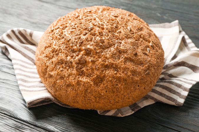 Bread on kitchen towel on wooden background, space for text and closeup