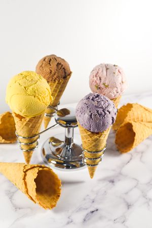 Ice cream cone stand with waffle cones and four different scoops, vertical