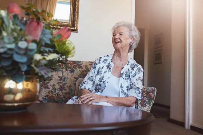 Mature woman smiling while sitting on a floral sofa
