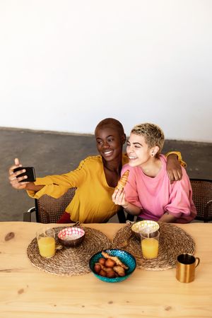 Two women taking selfie at breakfast together at home