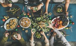 Group holding cocktails over table at festive table with candy canes and roasted pears