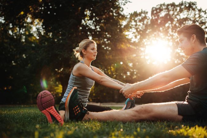 Smiling couple holding hands and stretching in morning