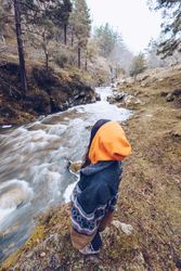 Woman gazing at fast mountain river in forest