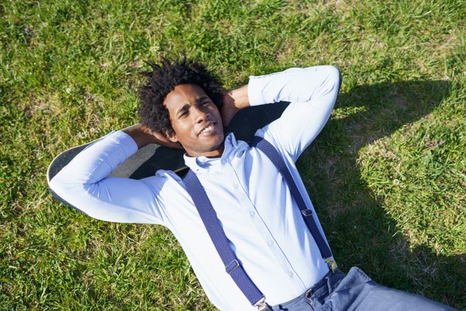Smiling man lying back on his skateboard