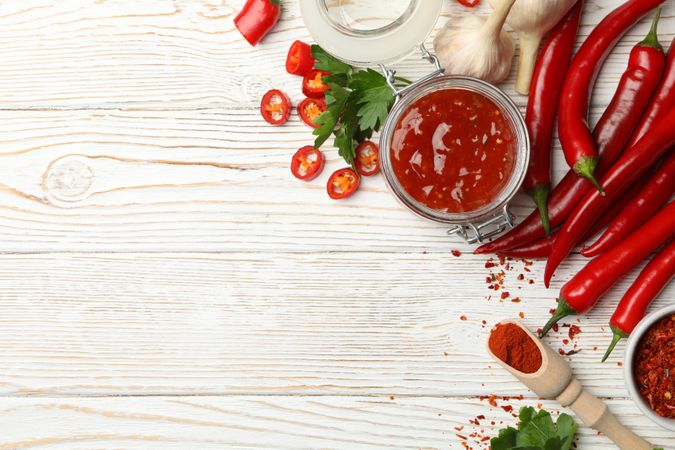 Composition with red hot sauce and ingredients on wooden background