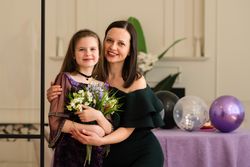 Girl and woman hugging and smiling at birthday party.