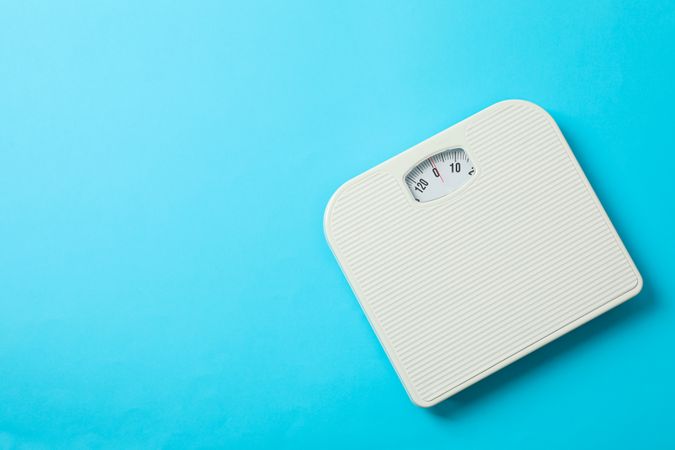 weigh scales on blue background, top view
