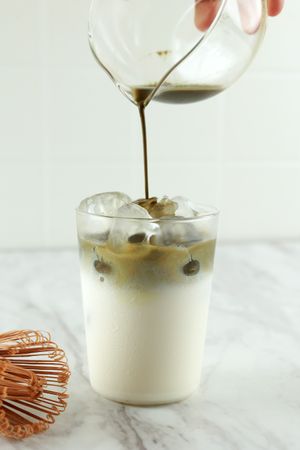 Pour Matcha Green Tea to the Milk on White Table,