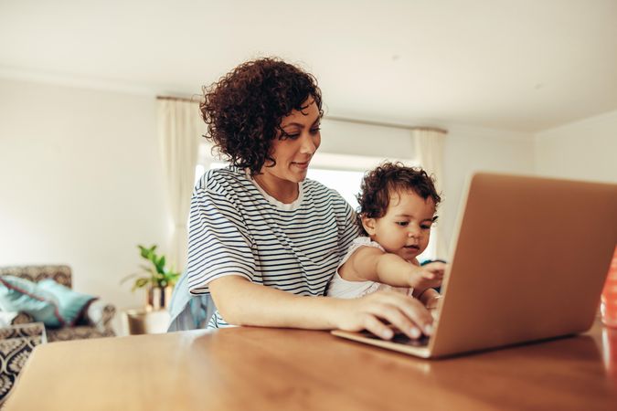 Woman with baby using laptop, working from home