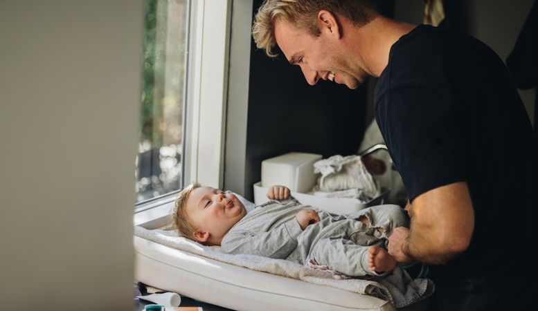 Man on paternity leave caring for his baby on changing table