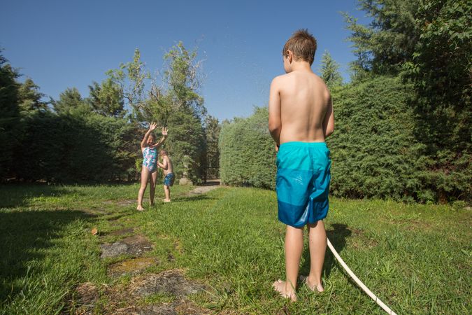Little kids in swimwear having fun with splashing water