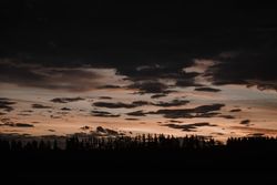 Evening cloudy sky above dark field