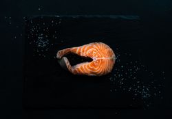 Top view of salmon steak on dark counter with copy space