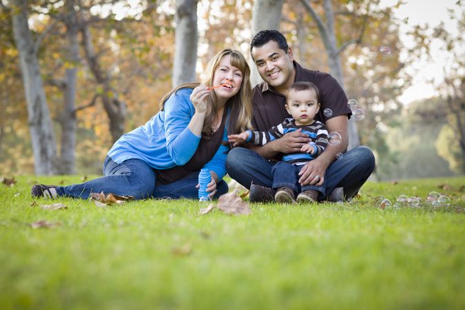 Smiling Family Playing with Bubbles In The Park