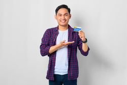 Asian male in grey studio presenting credit card