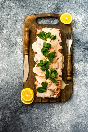 Top view of freshly baked lemon cake dessert with mint garnish on wooden board