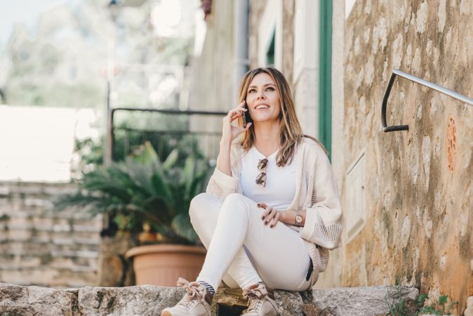 Woman with smartphone sitting on stone steps of stairs