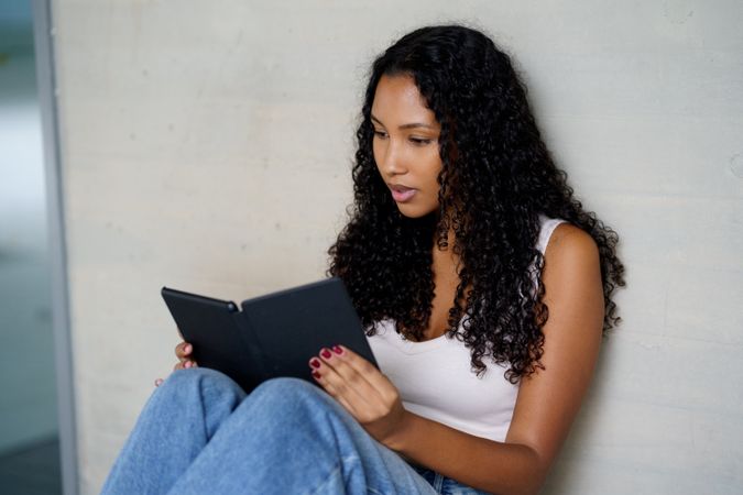 A young woman reads an engaging ebook in a cozy space, enjoying her leisure time
