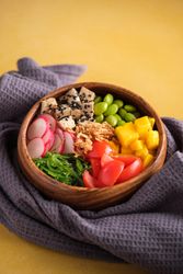 Healthy bowl with raw vegetables and mango on towel