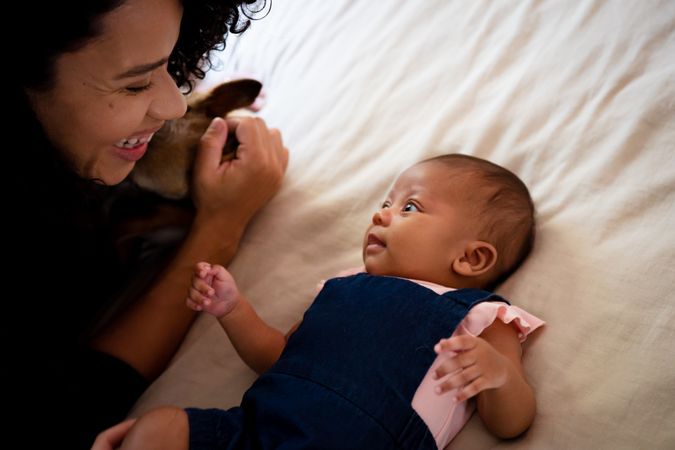 Smiling woman looking down at infant on bed