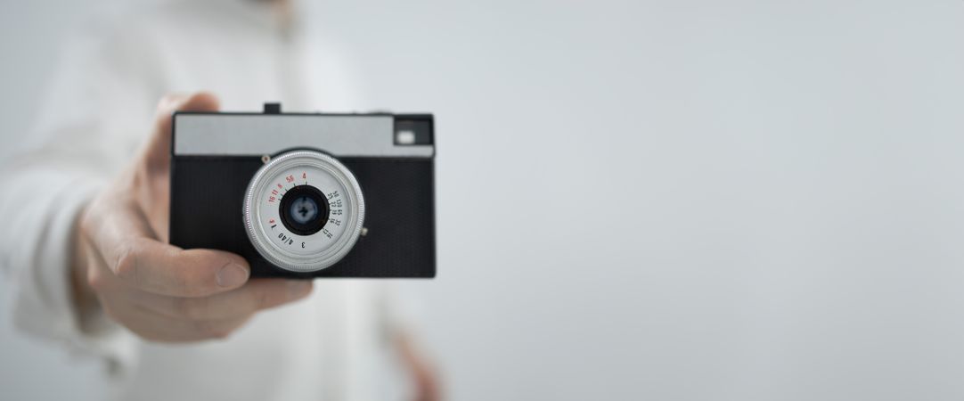 Man holding retro camera on light background