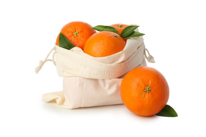 Cotton bag with ripe mandarins isolated on light background