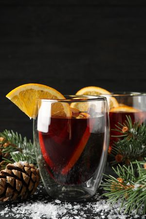Glasses of tasty mulled with orange on decorated background, space for text