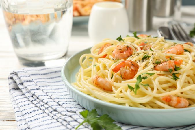 Composition with plate of tasty pasta with shrimps on wooden background