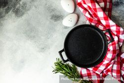 Top view of cast iron pan with rosemary and kitchen towel 47mkva